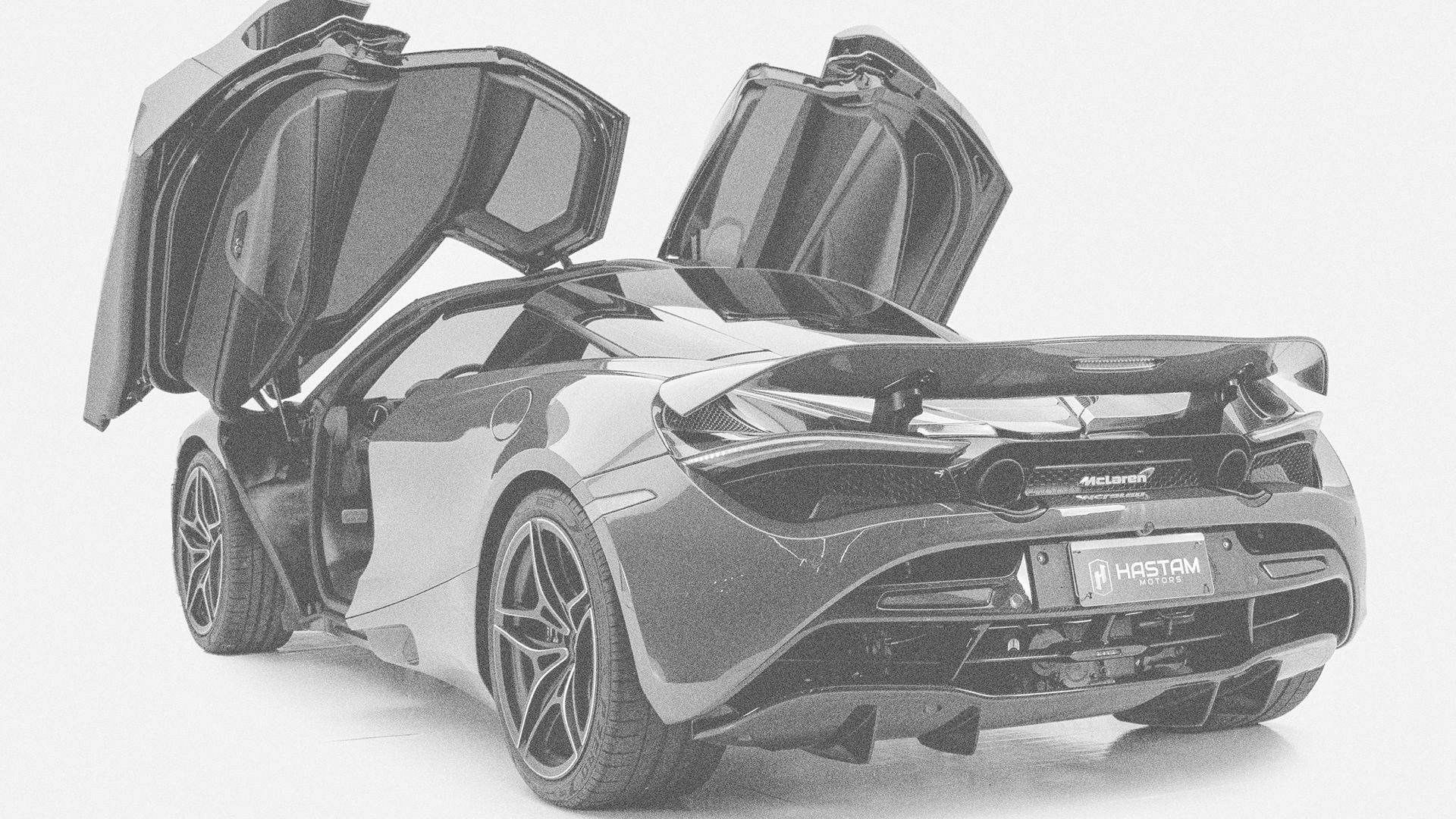 McLaren em preto e branco, portas abertas, com placa Hastam
